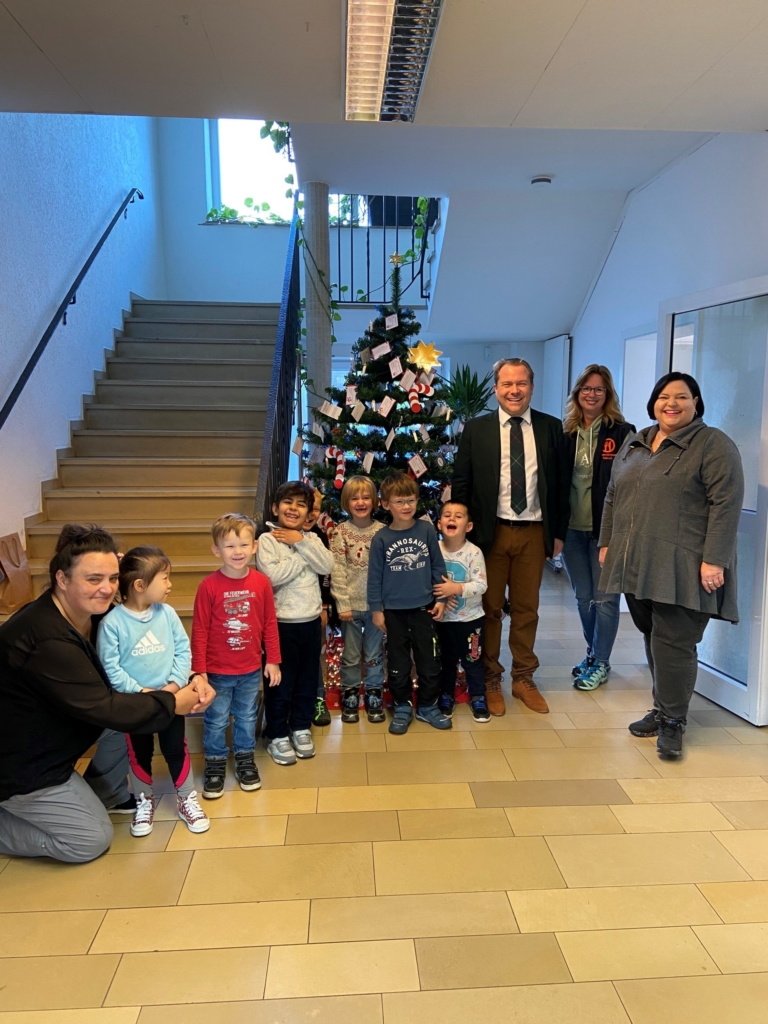 Bürgermeister und Kinder der Kita Sonnenhaus schmücken den Weihnachtswunschbaum der Tafel